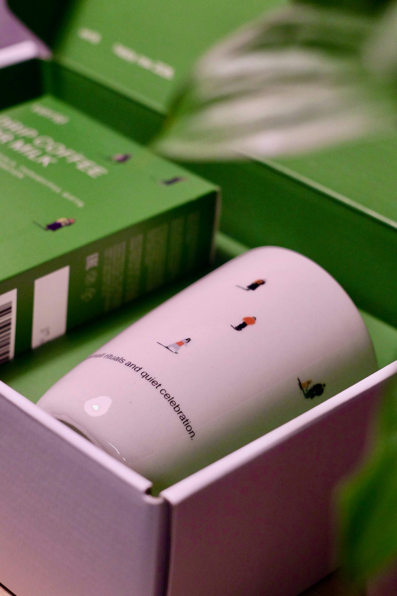 A white mug with small figures in a gift box.