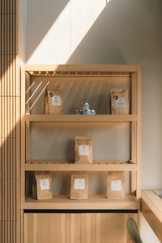 Sunlight illuminates wooden shelves with brown bags and blue containers.